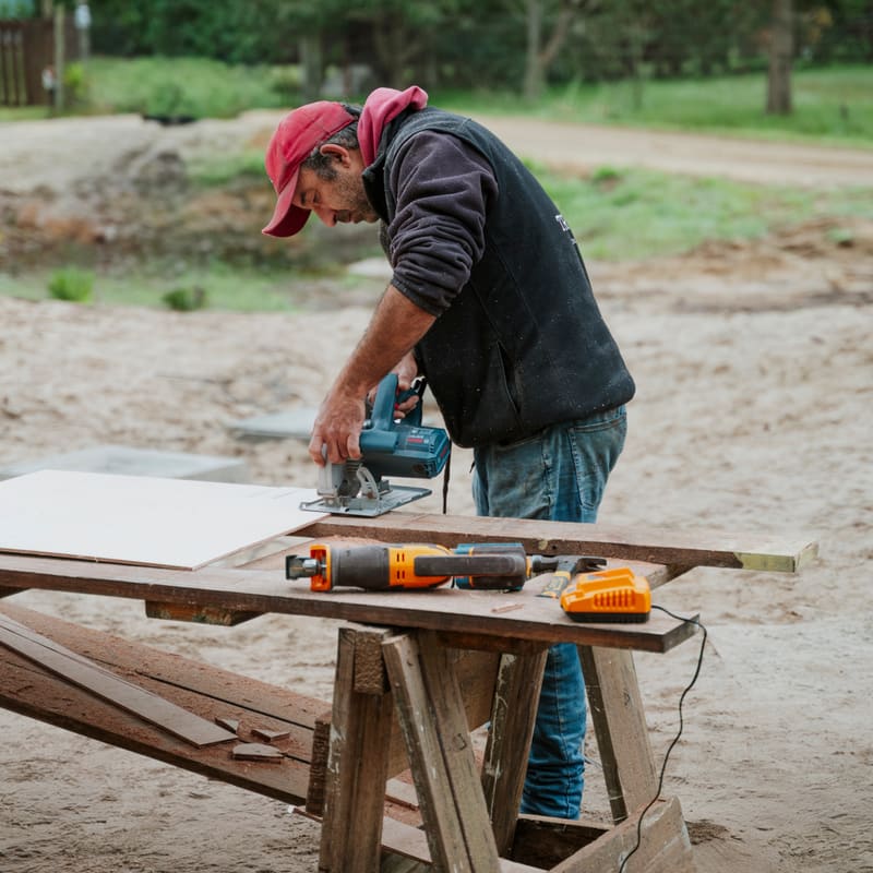 A carpenter cuts a board with a circular saw on the sawhorse.