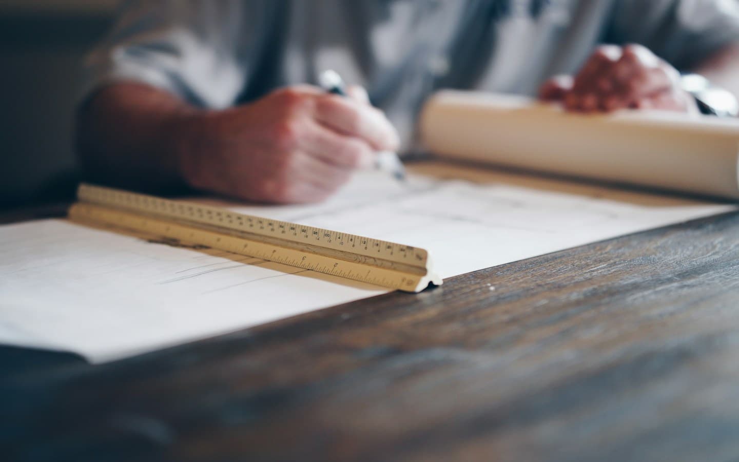 Hands on a building plan rolled out on a wooden table