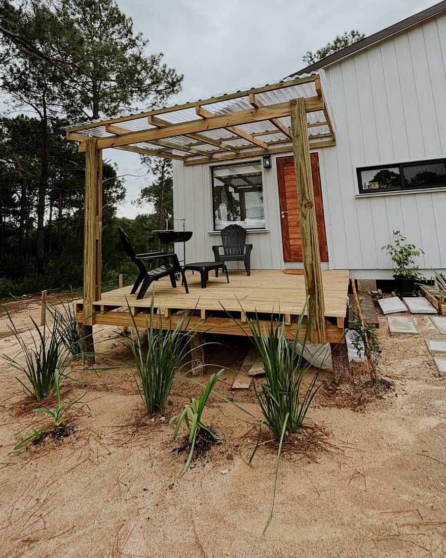 Finished timber house with a deck and a pergola among pines.