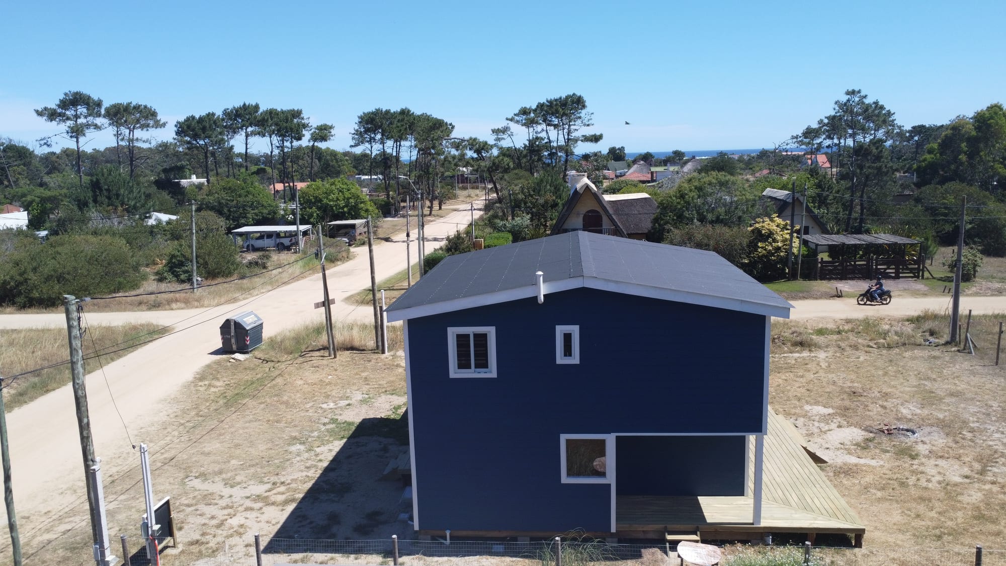 Casa Azul in context from the air: a sand path, pine forest and the sea on the horizon.