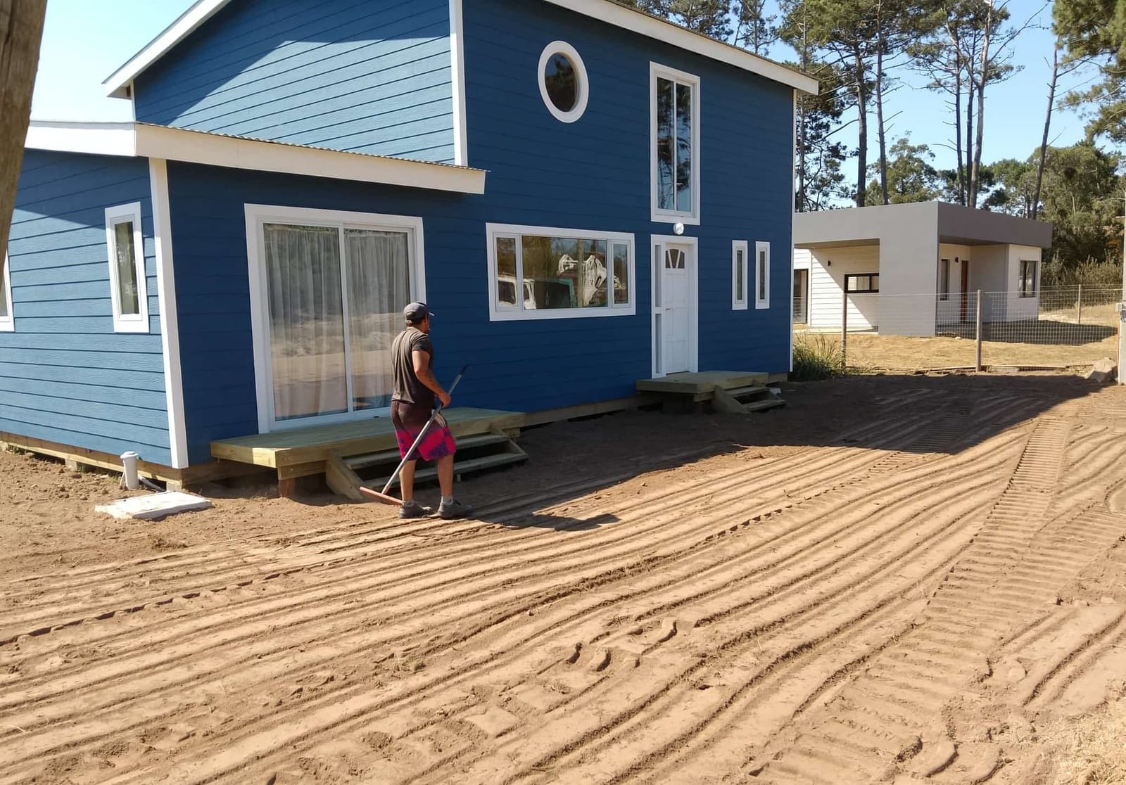 A worker levels the sandy ground in front of Casa Azul.