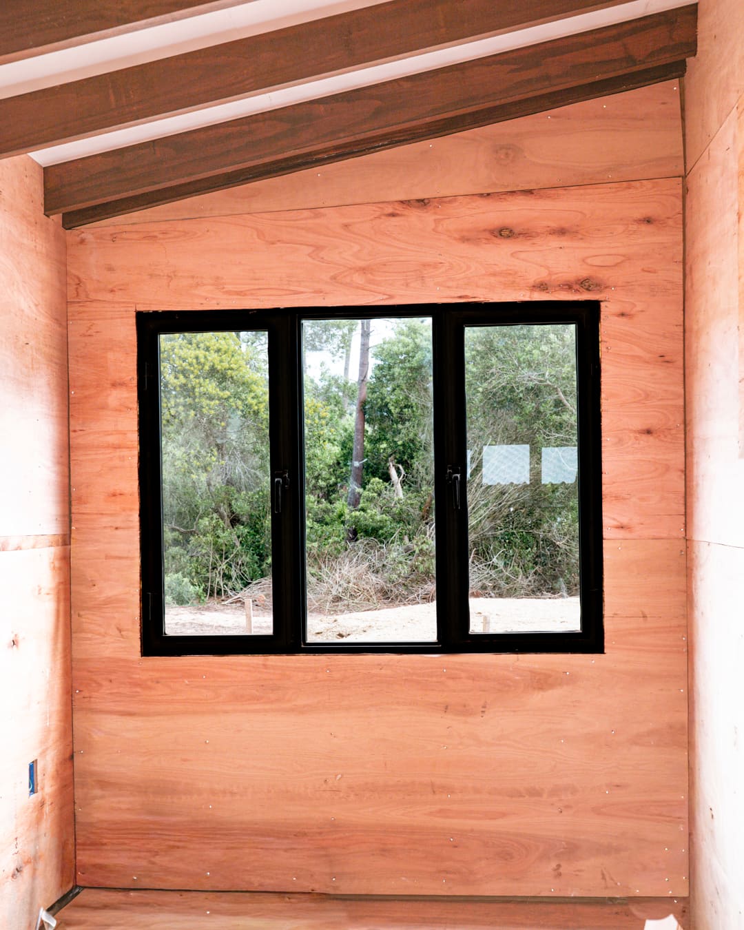 Wall lined with timber panels and a black three-part window.