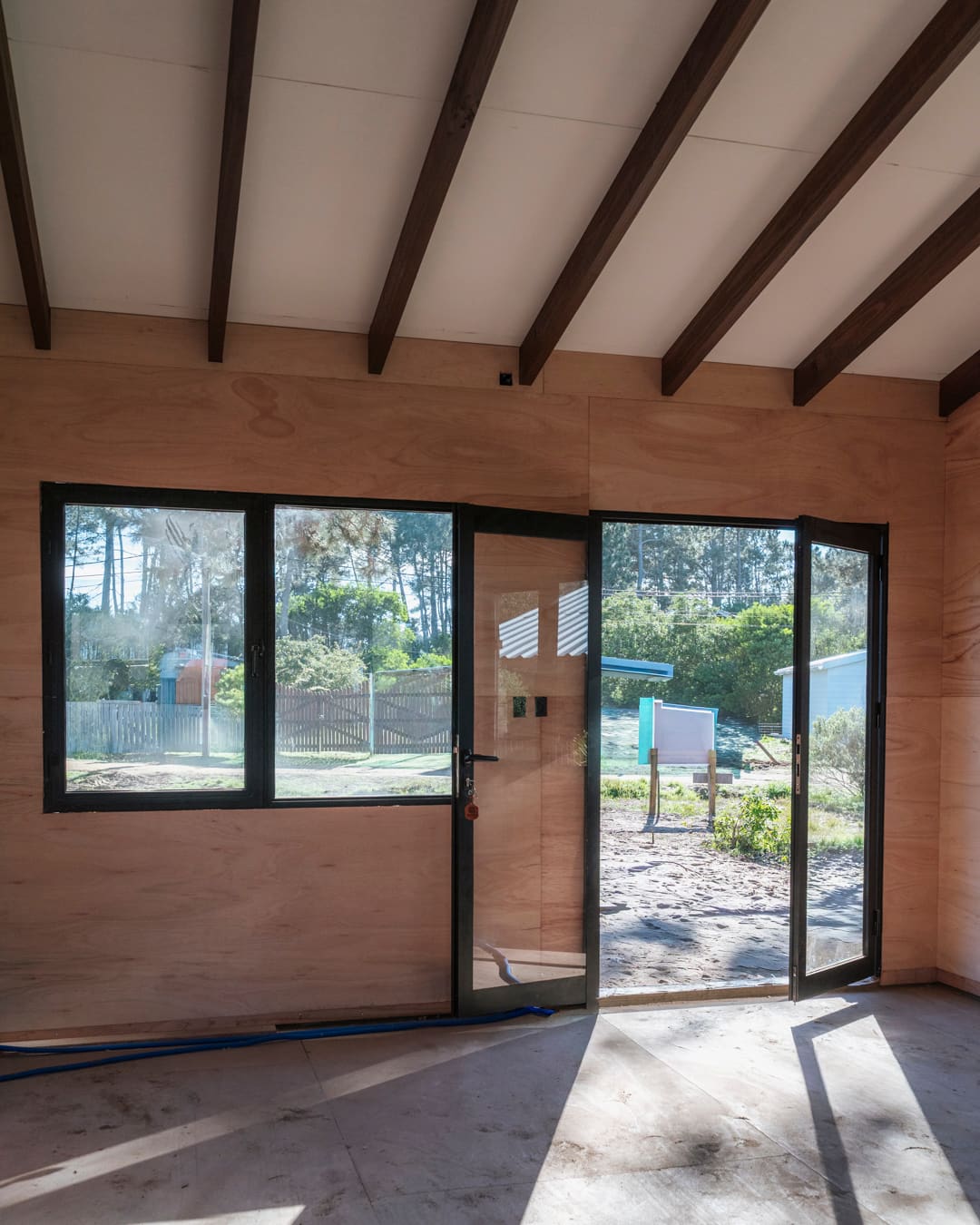 Lined room with a window and an open glass door, light falling across the floor.