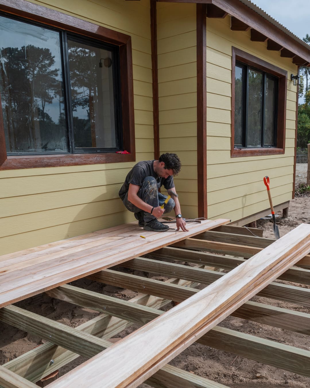 Worker laying deck boards on the substructure along the facade.